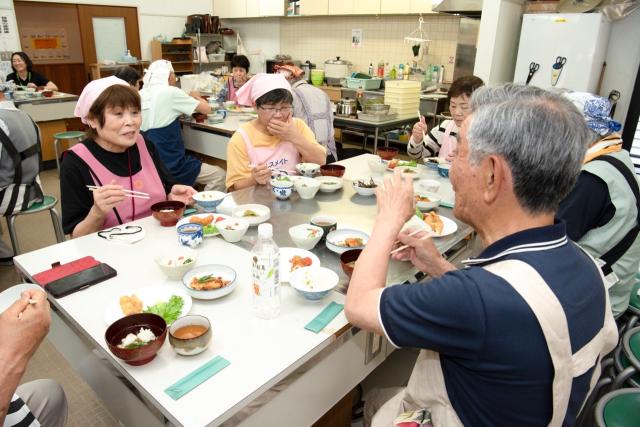 自分たちで作った料理をおしゃべりしながら食べる人々1