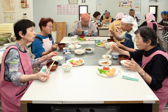 自分たちで作った料理をおしゃべりしながら食べる人々2